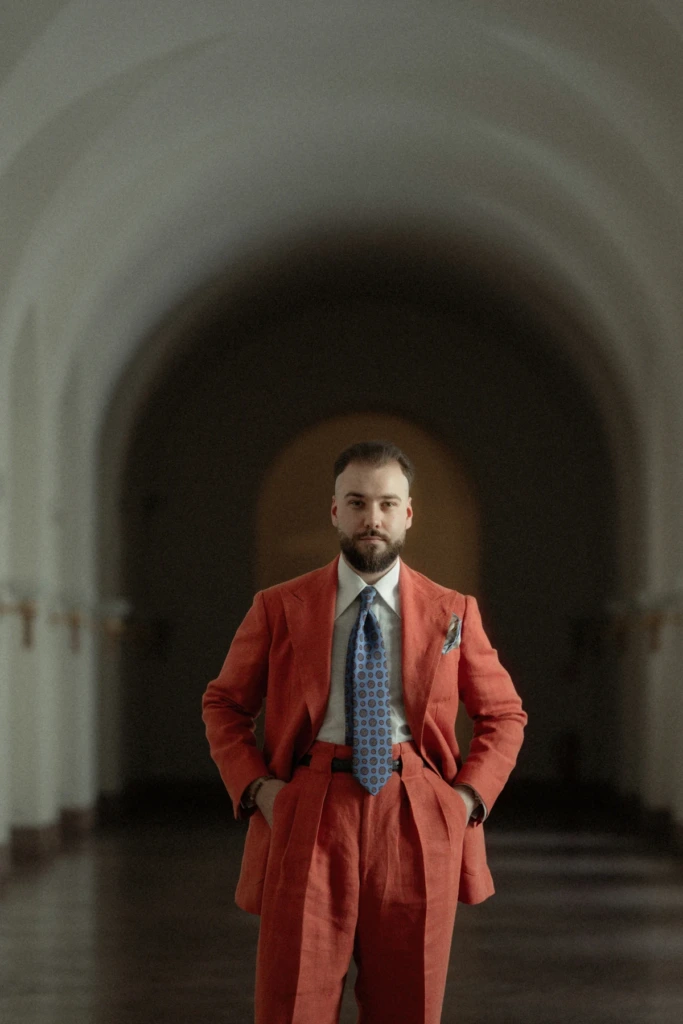 Pomarańczowy garnitur lniany w zamku, portret, biała koszula i błękitny jedwabny krawat.